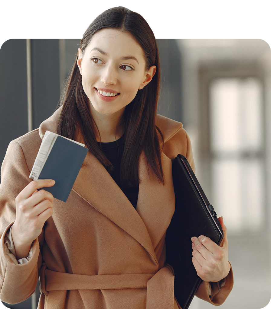 Woman in beige coat holding passport and folder, smiling in an indoor setting.