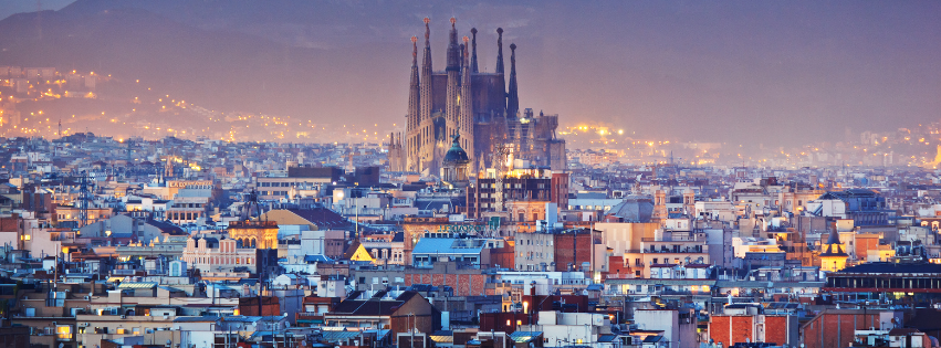 Panoramic view of Barcelona cityscape at dusk with the iconic Sagrada Família basilica in the background.